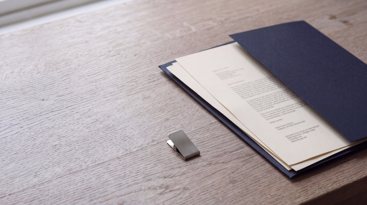 Ivory document pages in a navy folder on a pale wooden desk beside a window.