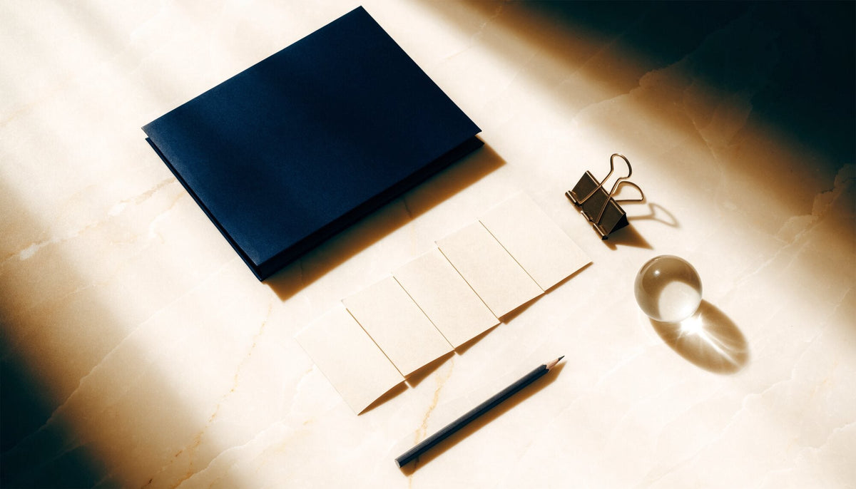 Navy document folio, blank ivory evidence cards and a bronze clip on a pale stone desk.